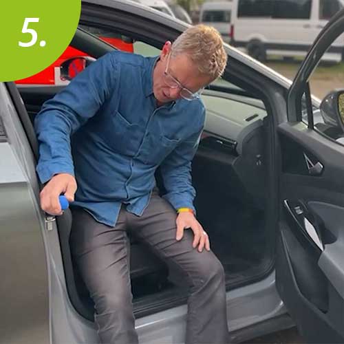 Mann stützt sich auf einen Griff ab, um aus dem Fahrzeug zu gelangen