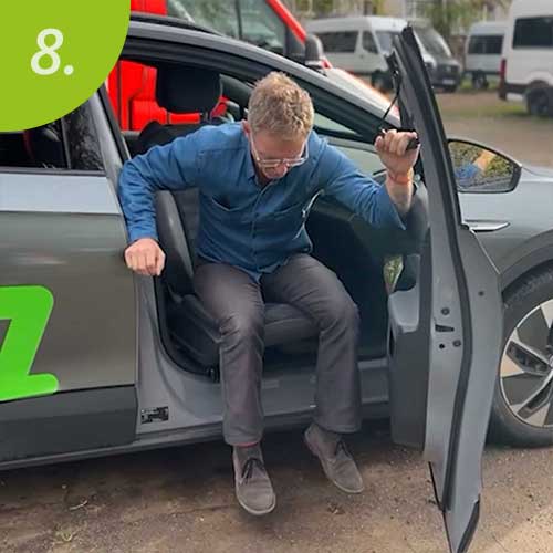 Mann hält sich an Haltegriff fest und steigt aus dem Auto aus