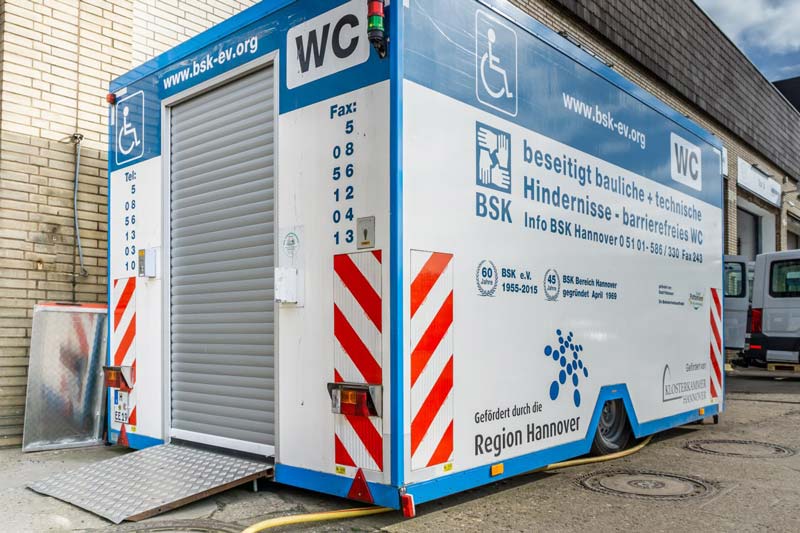 Eine mobile behindertengerechte Toilette steht auf einem Hof